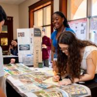two students present to their peers with posters from student project showcase